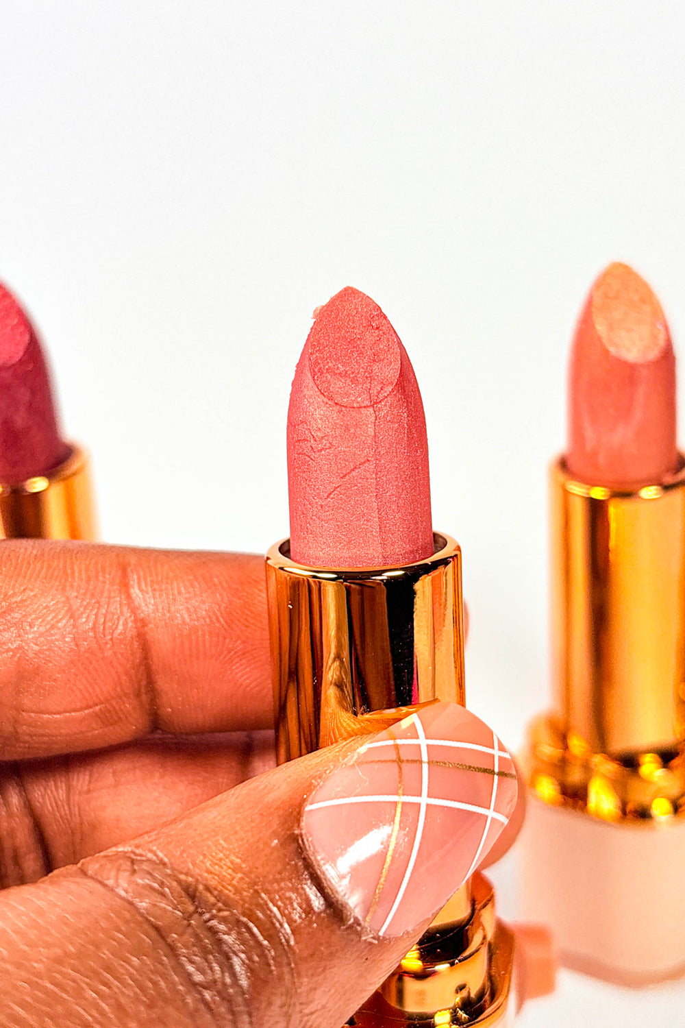 Lipstick with gold casing and visible brand name on a white background Bare Blossom Lipstick Naaby