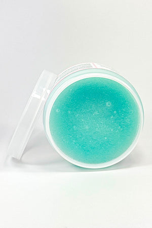 Turquoise-colored cosmetic product in a clear container on a white background.Berry Boujee – Foaming Sugar Body  Scrub