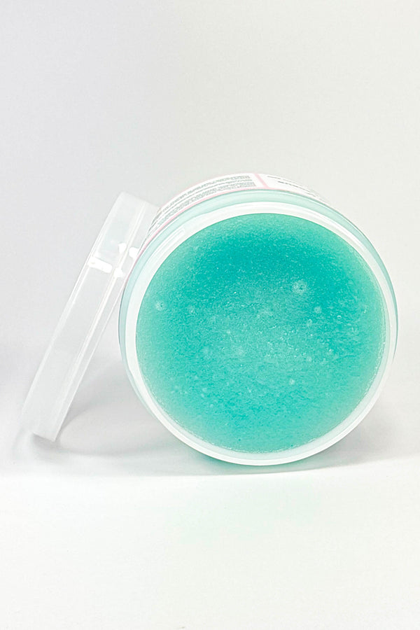 Turquoise-colored cosmetic product in a clear container on a white background.Berry Boujee – Foaming Sugar Body  Scrub