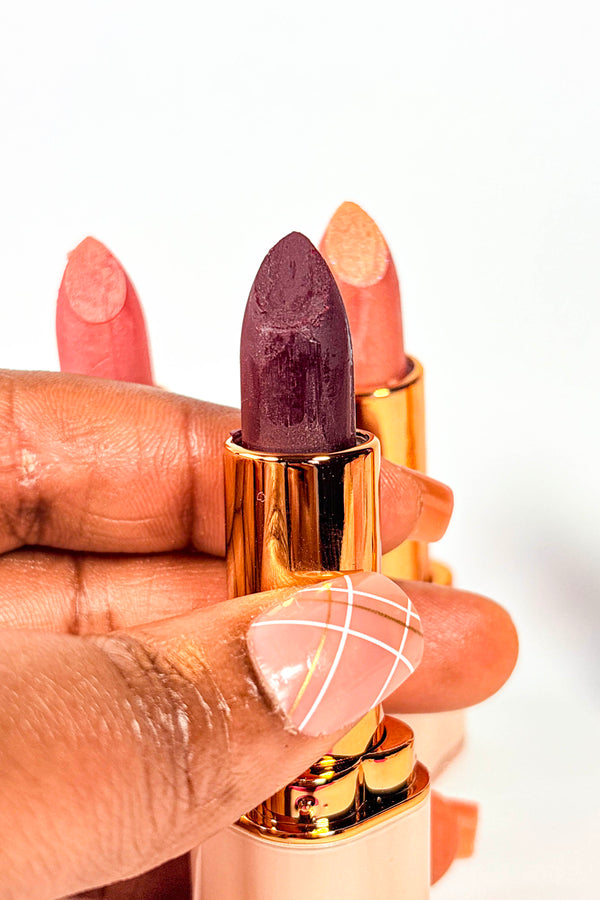 Lipstick held by a hand with a white background. Crimson Velvet Lipstick