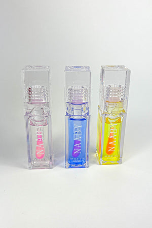 Three transparent cosmetic bottles with colorful labels on a white background-Bleeding Heart color changing lip oil