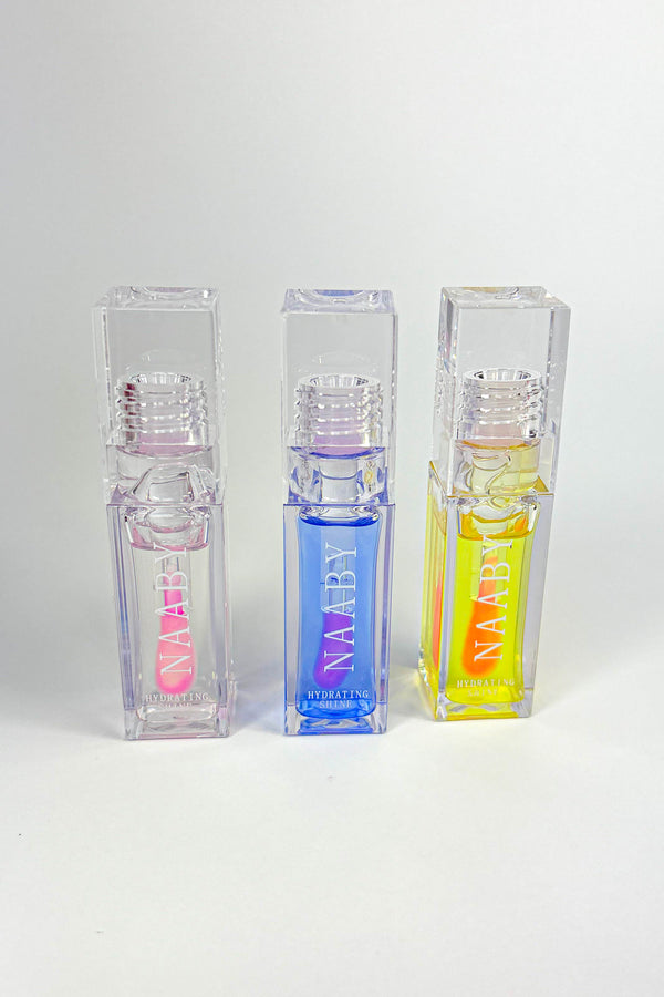 Three transparent cosmetic bottles with colorful labels on a white background-Bleeding Heart color changing lip oil