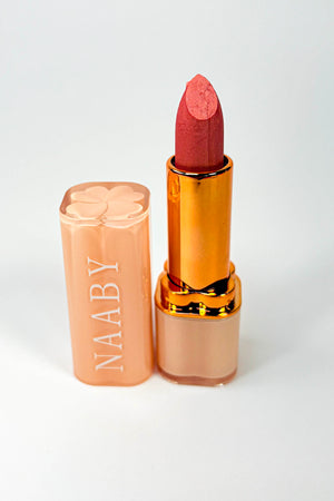 Lipstick with gold casing and visible brand name on a white background Bare Blossom Lipstick Naaby