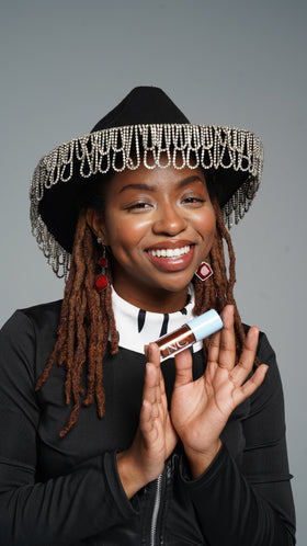 Person with braided hair holding a product against a gray background