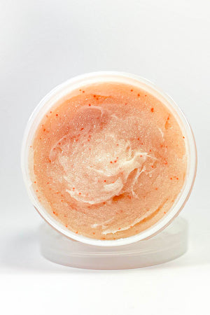 Jar of peach-colored scrub on a white background