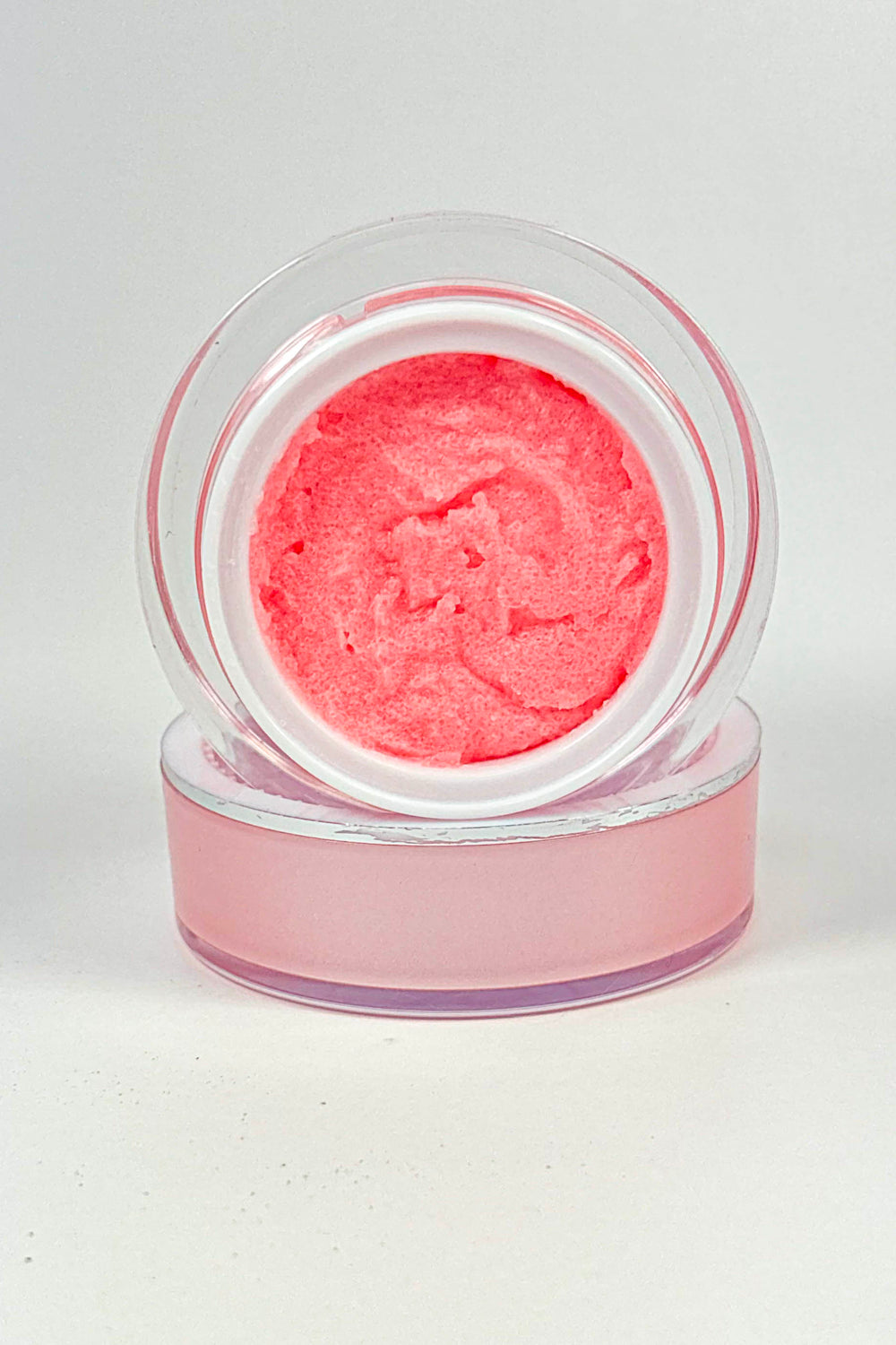 Pink cosmetic product in a clear container on a white background