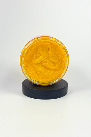 Round yellow object on a black stand against a white background-Turmeric Glow Scrub – Brightening Turmeric Sugar Scrub for Dark Spots