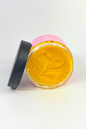 Jar of gold powder with a pink lid on a white background Turmeric_Glow_Scrub_Brightening_Turmeric_Sugar_Scrub_for_Dark_Spots