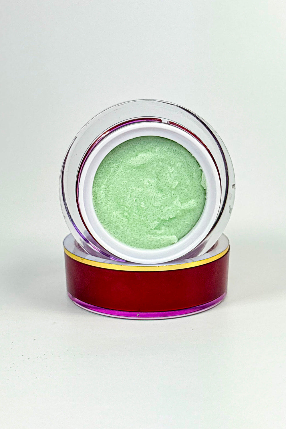 Green cream in a clear jar with a red lid on a white background-Vegan Peppermint Sugar Lip Scrub – Natural Lip Exfoliator for Soft, Smooth Lips