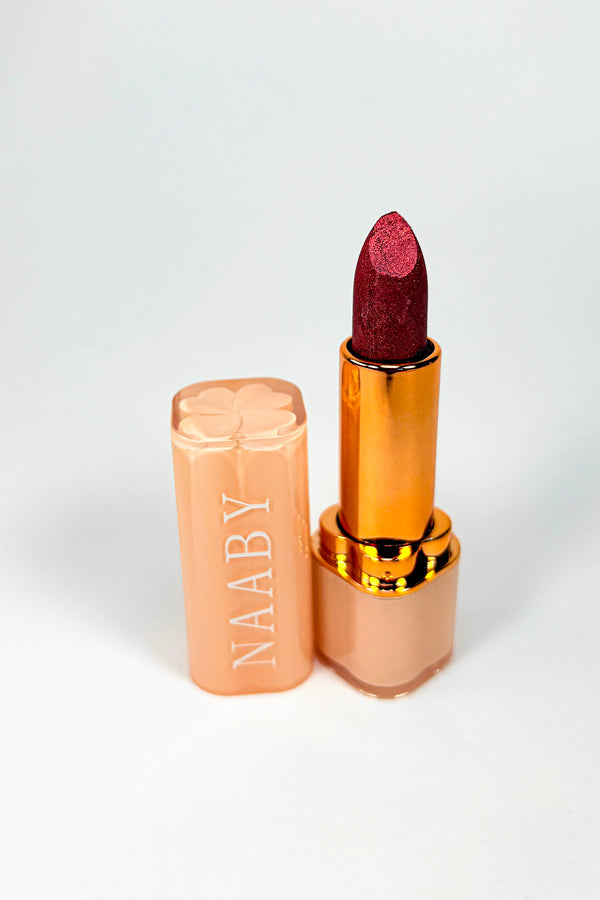 Lipstick with gold cap and NAABY branding on a white background. Velvet Truffle Lipstick