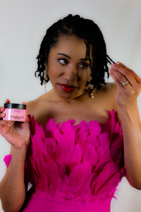 Woman in a bright pink dress holding a pink jar with a white background