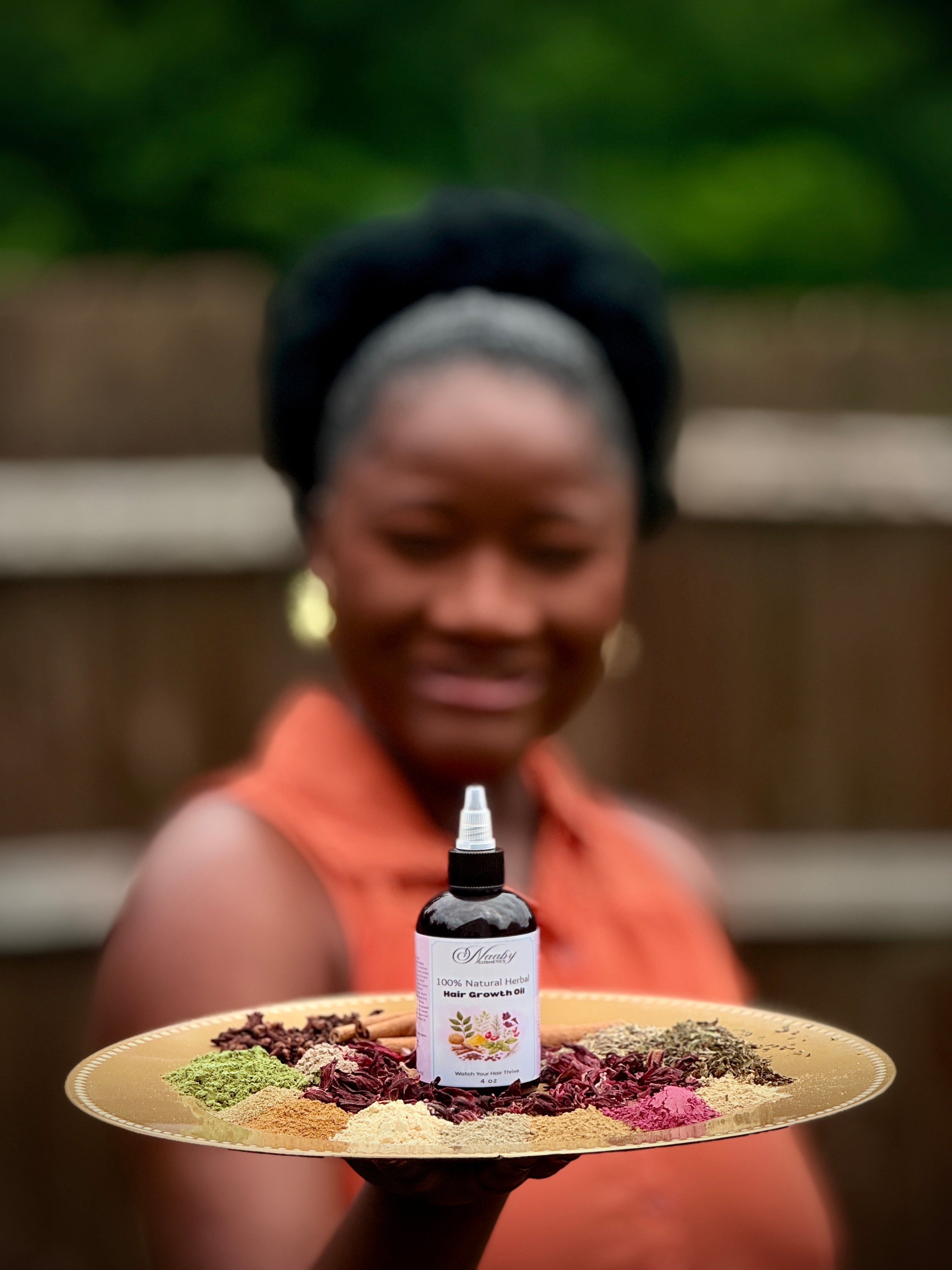 Woman holding a tray with a bottle of Wildwood Naturals product and herbs.