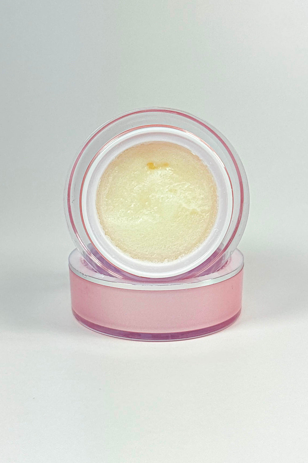 Cosmetic cream in a clear container with a pink lid on a white background.lemon Sugar Lip Scrub – Natural Lip Exfoliator for Soft, Smooth Lips
