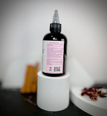 Tattoo ink bottle with a label on a white cylindrical stand against a neutral background
