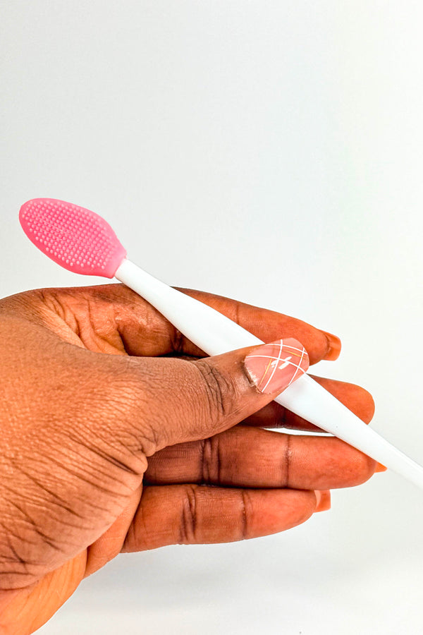 Hand holding a white and pink silicone spatula against a white background