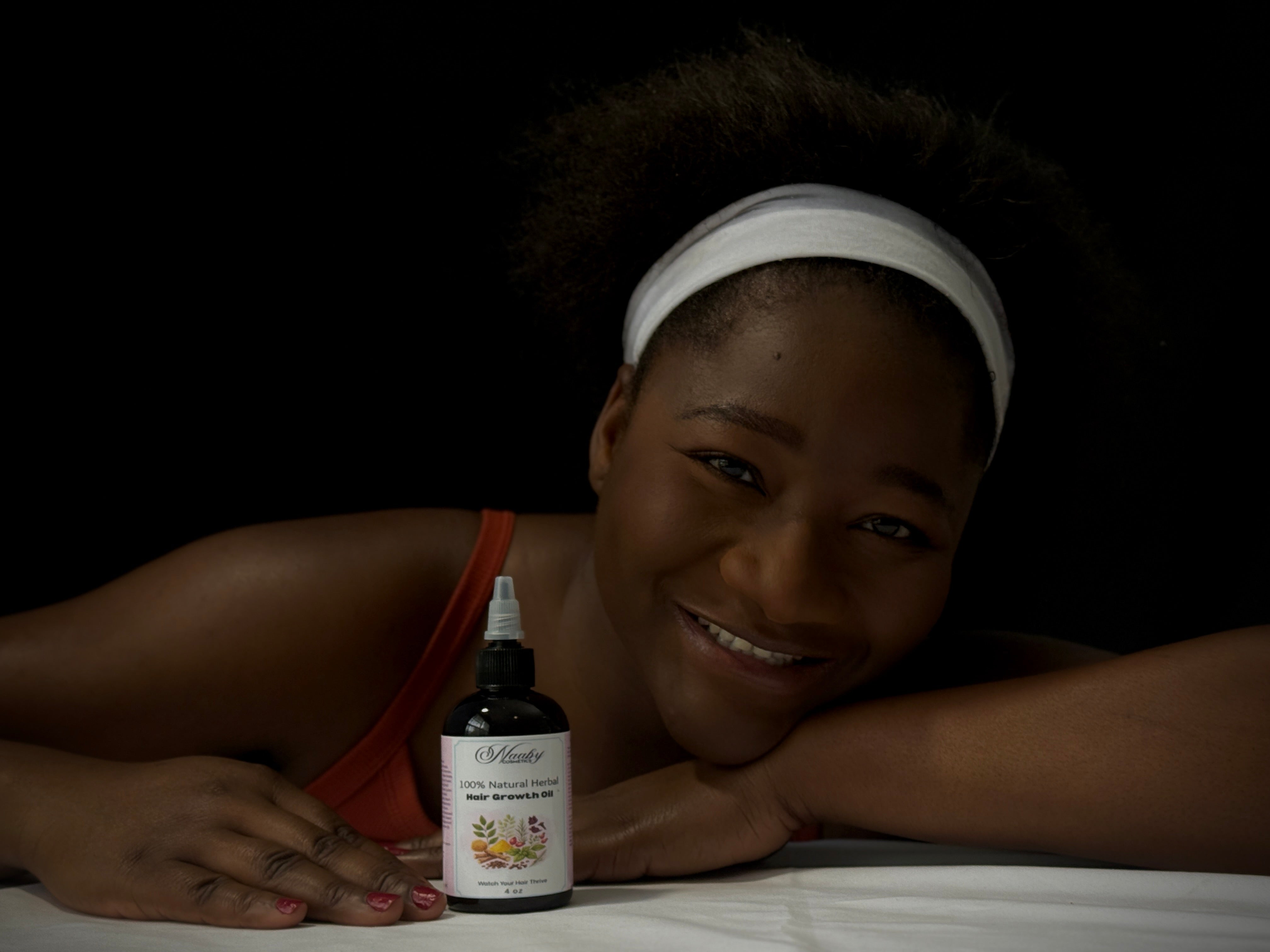 Woman holding a bottle of M. Micallef skincare product against a dark background